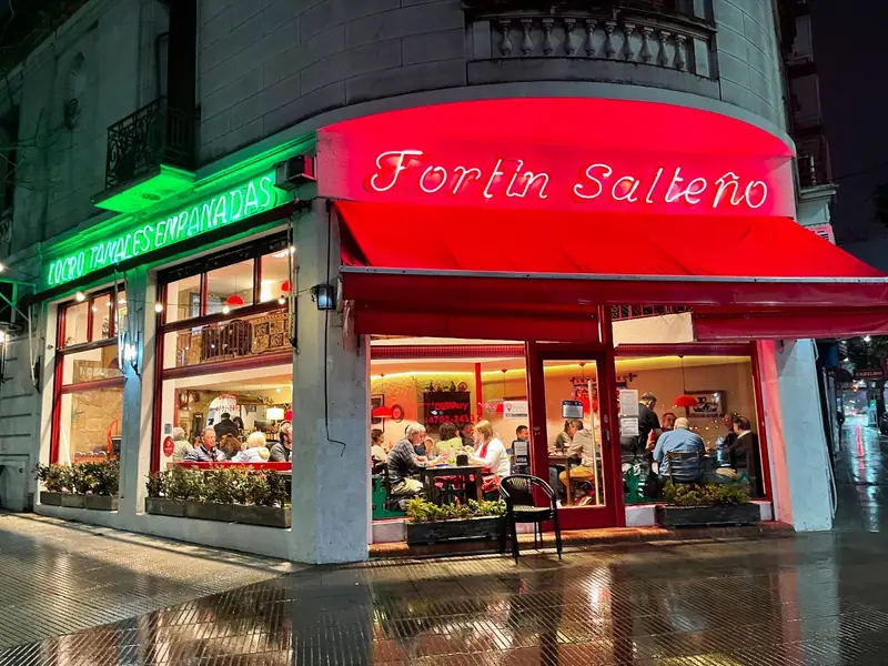 Frente iluminado de Fortín Salteño sobre Av. Cabildo, en Núñez, de noche